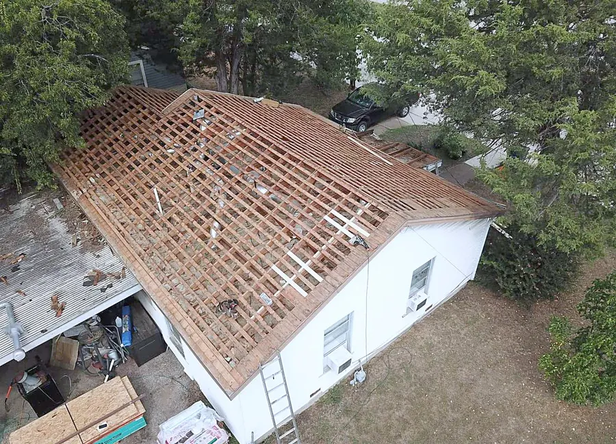 An old roof torn off down to the rafters, photographed by drone